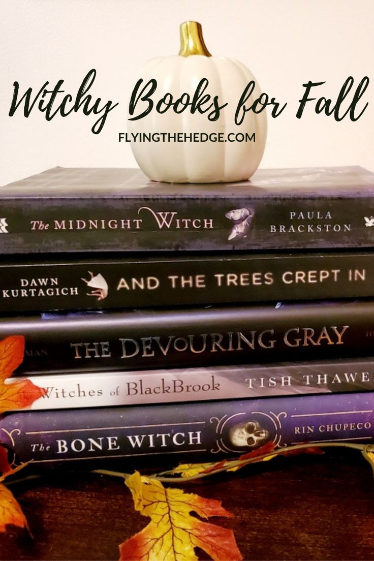 a stack of books sitting on top of a wooden table next to a white pumpkin