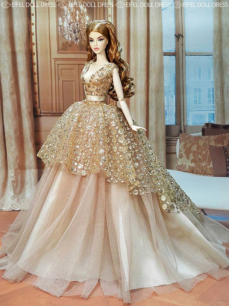 a barbie doll wearing a gold and white dress in front of a chandelier