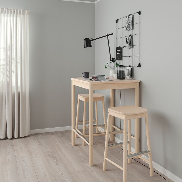 two stools sit at the end of a small table in front of a window