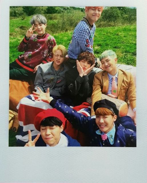 a group of young men sitting next to each other on top of a grass covered field