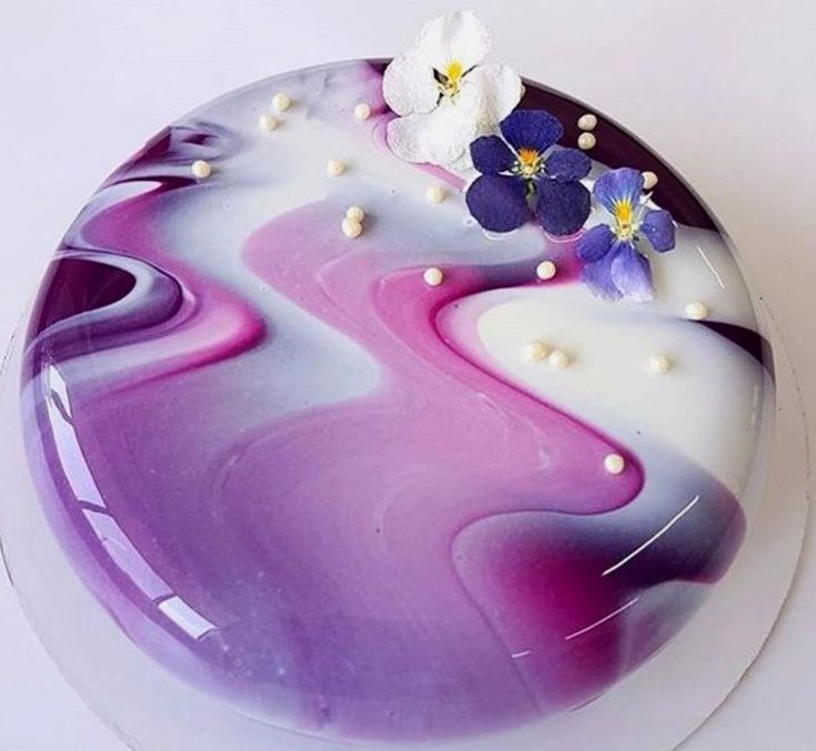 a cake with purple and white frosting on the top, decorated with pansies