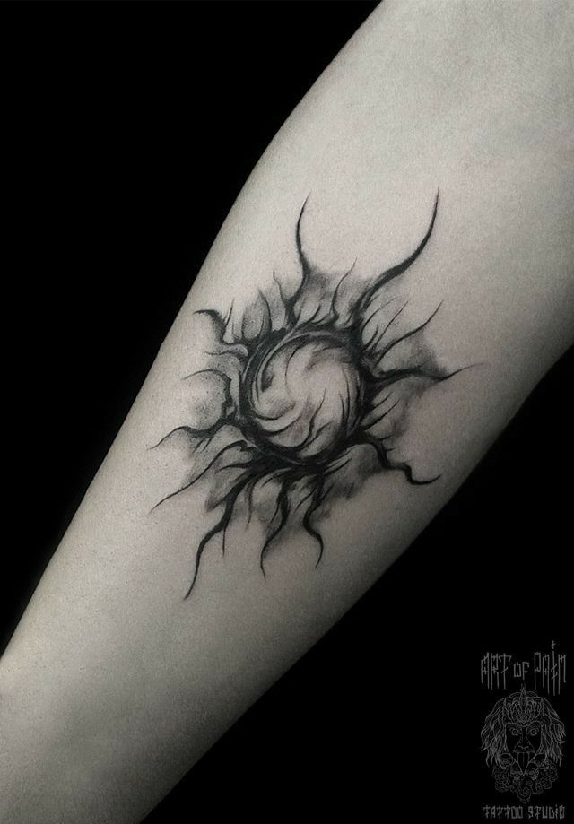 a black and white photo of a sun tattoo on the arm