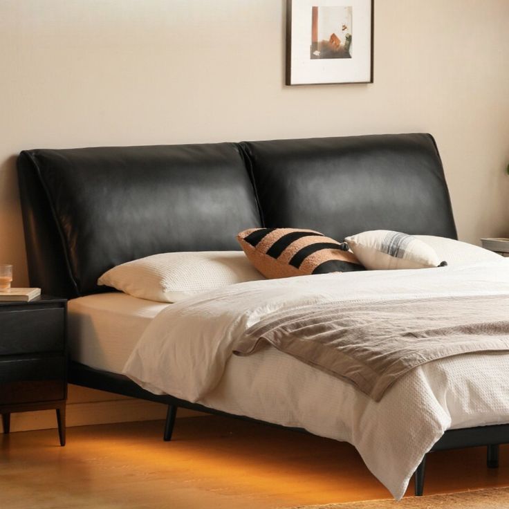 a bed with black leather headboard and foot board