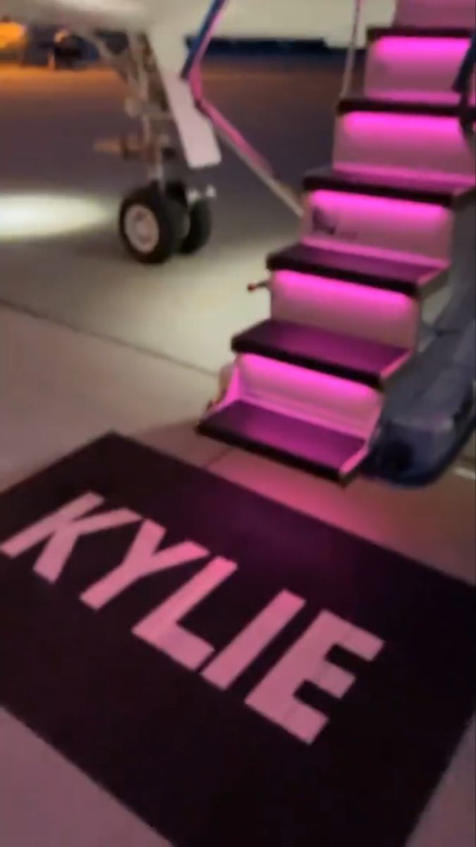 an airplane is parked at the airport with its stairs lit up and pink lights on it