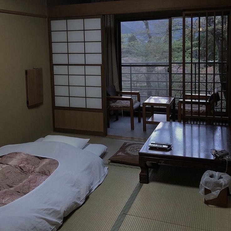 a bed sitting in a bedroom next to a wooden table and chair near a sliding glass door