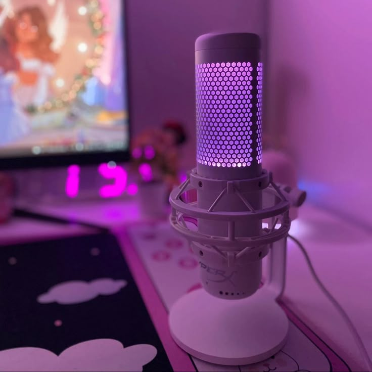 a close up of a microphone on a desk with a computer in the back ground