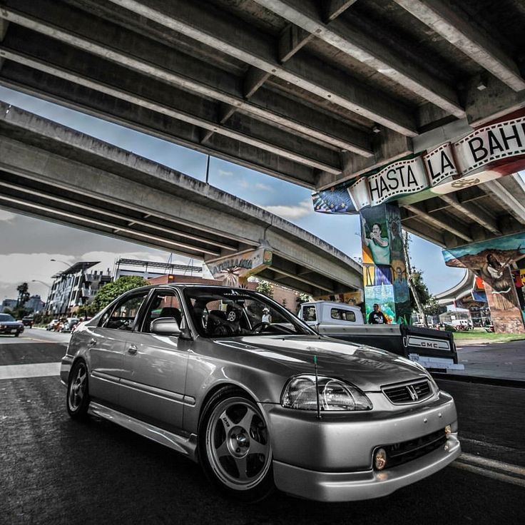 a silver car parked in front of an overpass