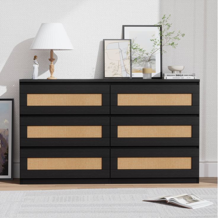 a black and gold dresser in a white room with pictures on the wall next to it