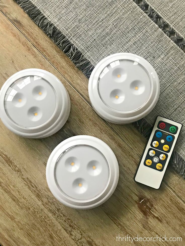 three white lights sitting on top of a wooden table next to a remote control and a rug