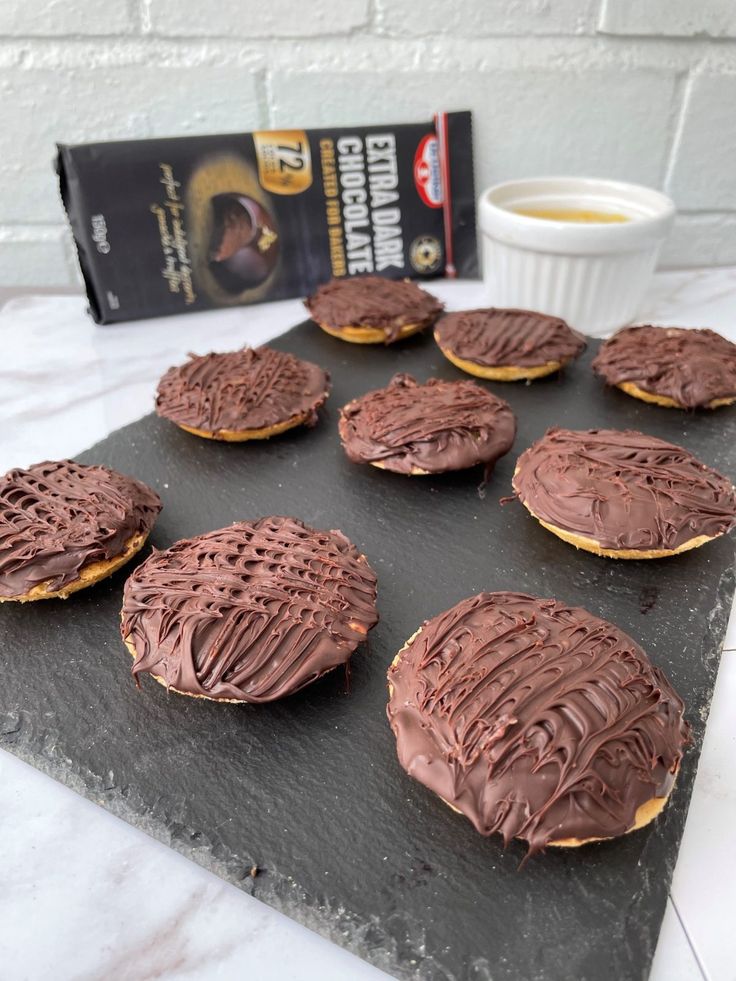 chocolate covered cookies sitting on top of a cookie sheet next to a cup of coffee