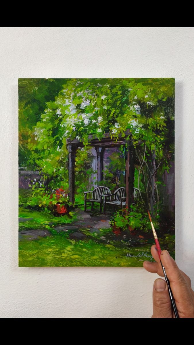 a person holding a paintbrush in their hand while painting a garden scene on the wall