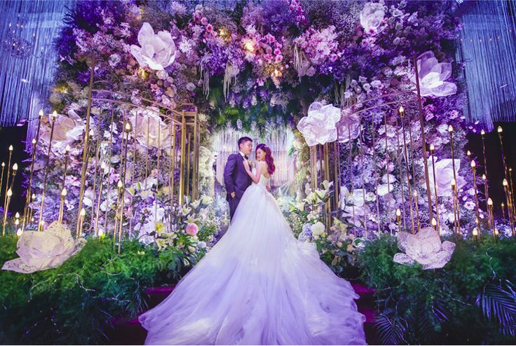 a bride and groom standing in front of an elaborate floral backdrop at their wedding reception