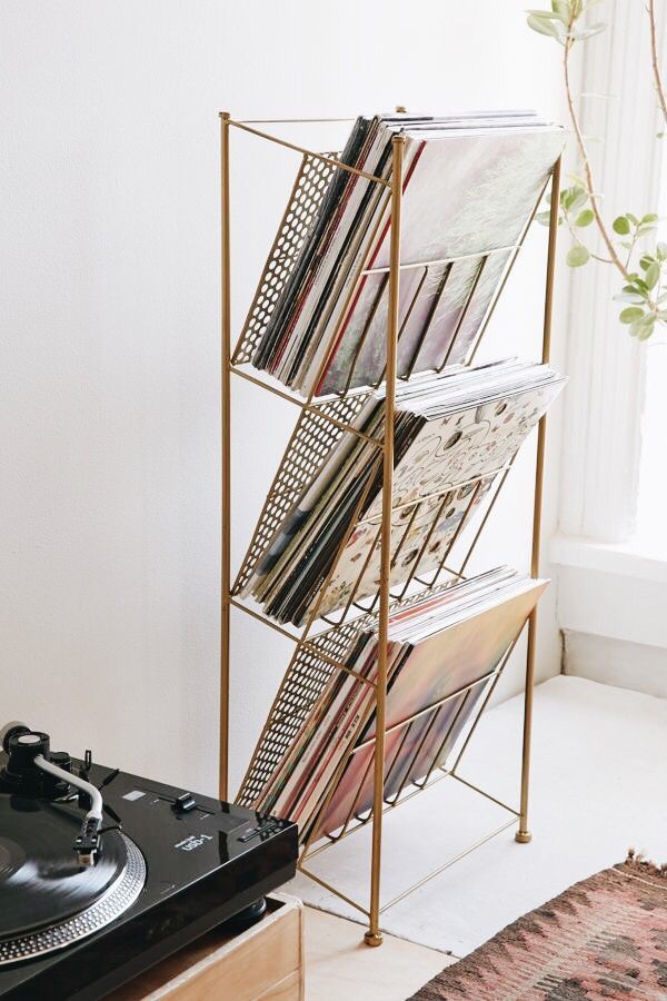 a record player sitting on top of a wooden table next to a metal rack filled with records