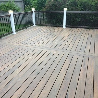 a wooden deck with white railings and black iron fencing on it's sides