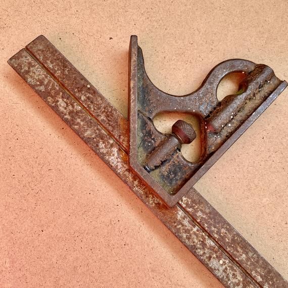 an old pair of scissors sitting on top of a piece of rusted metal with holes in the middle