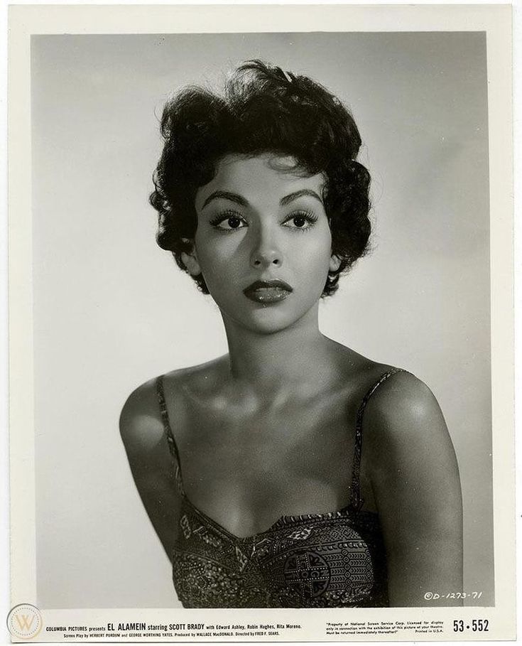 a black and white photo of a woman with short hair in a bra top looking at the camera