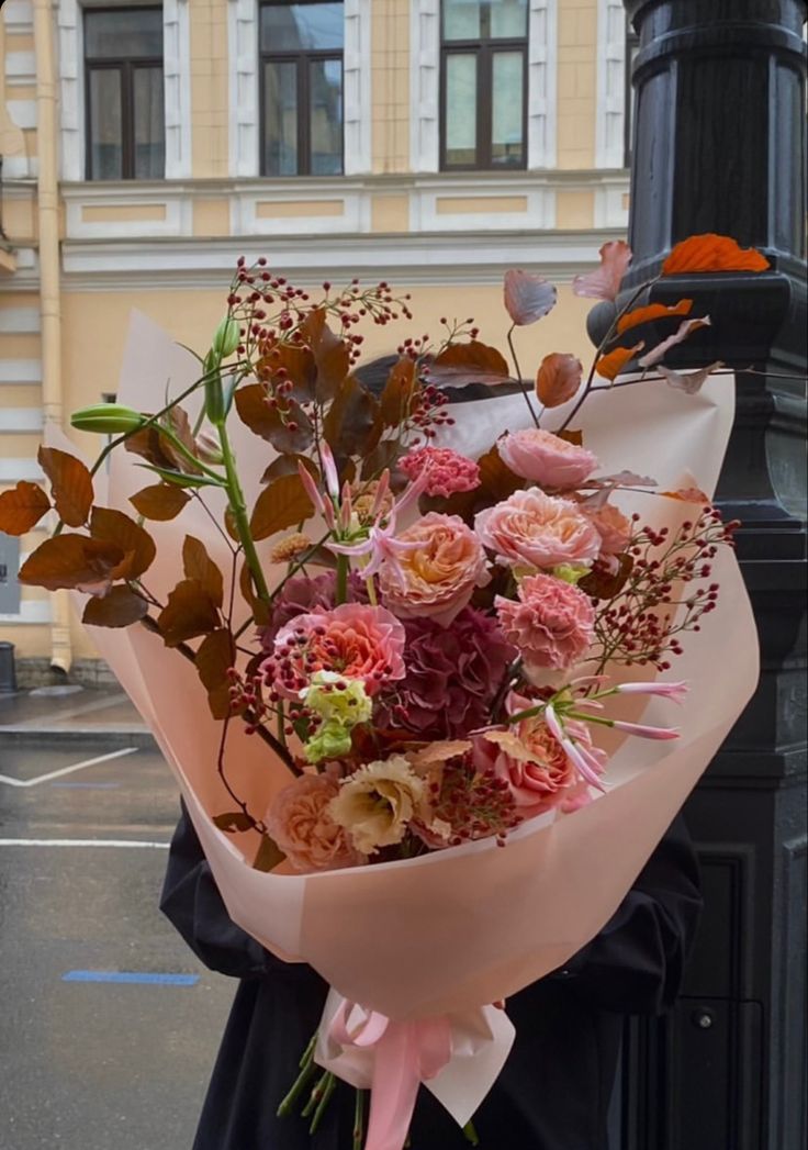 a woman holding a bouquet of flowers on top of a street pole in front of a building