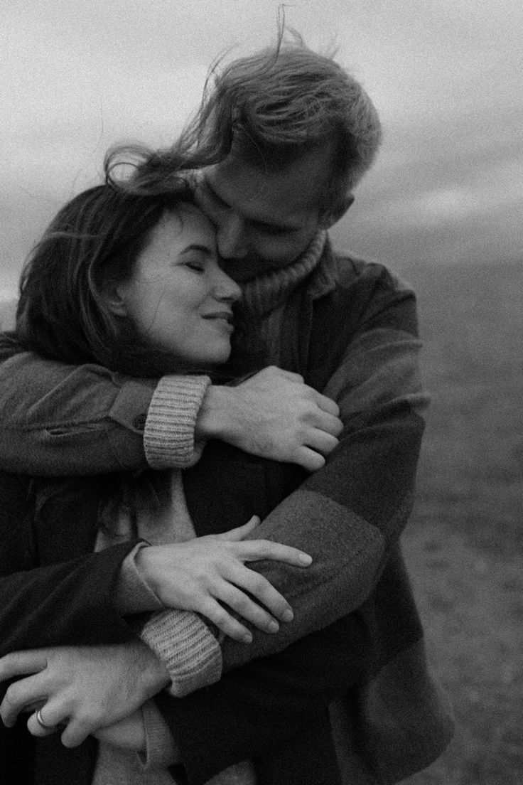 black and white photograph of a couple embracing each other in front of an overcast sky