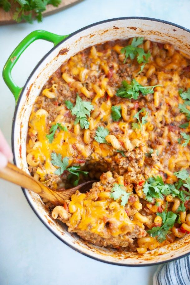 a green skillet filled with taco meat and cilantro garnished with parsley