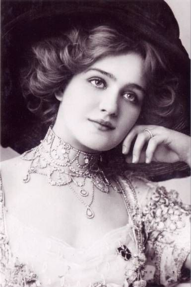 an old fashion photo of a woman wearing a hat and dress with flowers on it