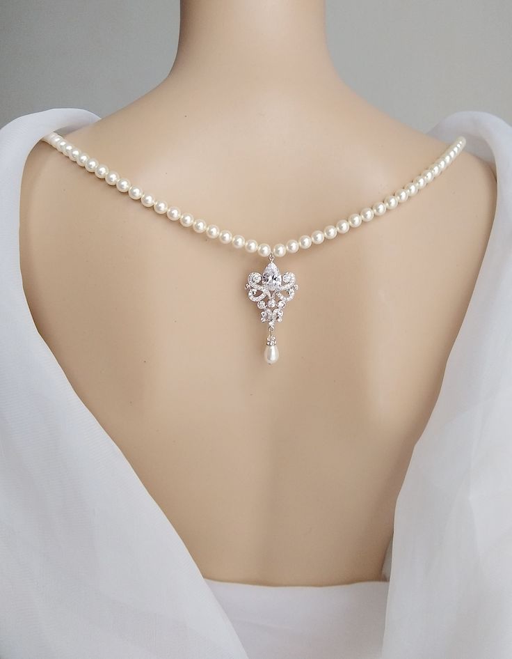 a woman wearing a white dress with a cross on it's neck and pearl necklace