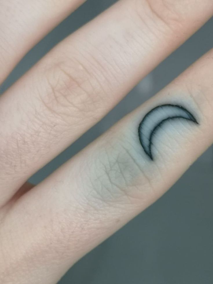 a person's hand with a small wave tattoo on the middle finger and ring