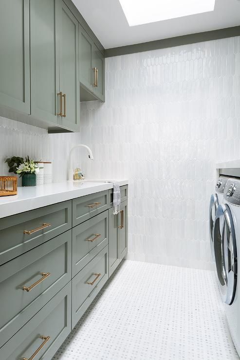 a washer and dryer in a room with green cabinetry, white counter tops and tile flooring