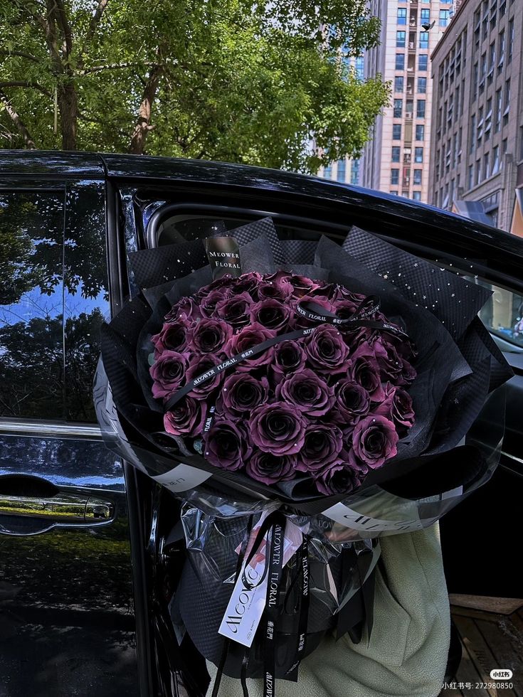 a bouquet of purple roses is placed in the back of a black car on a city street