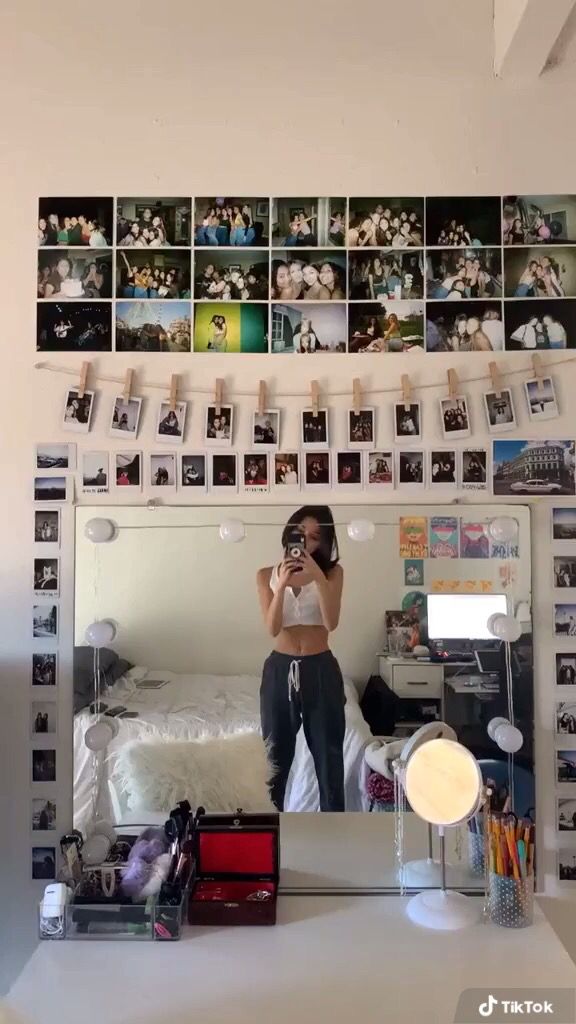 a woman taking a selfie in front of a mirror with pictures on the wall