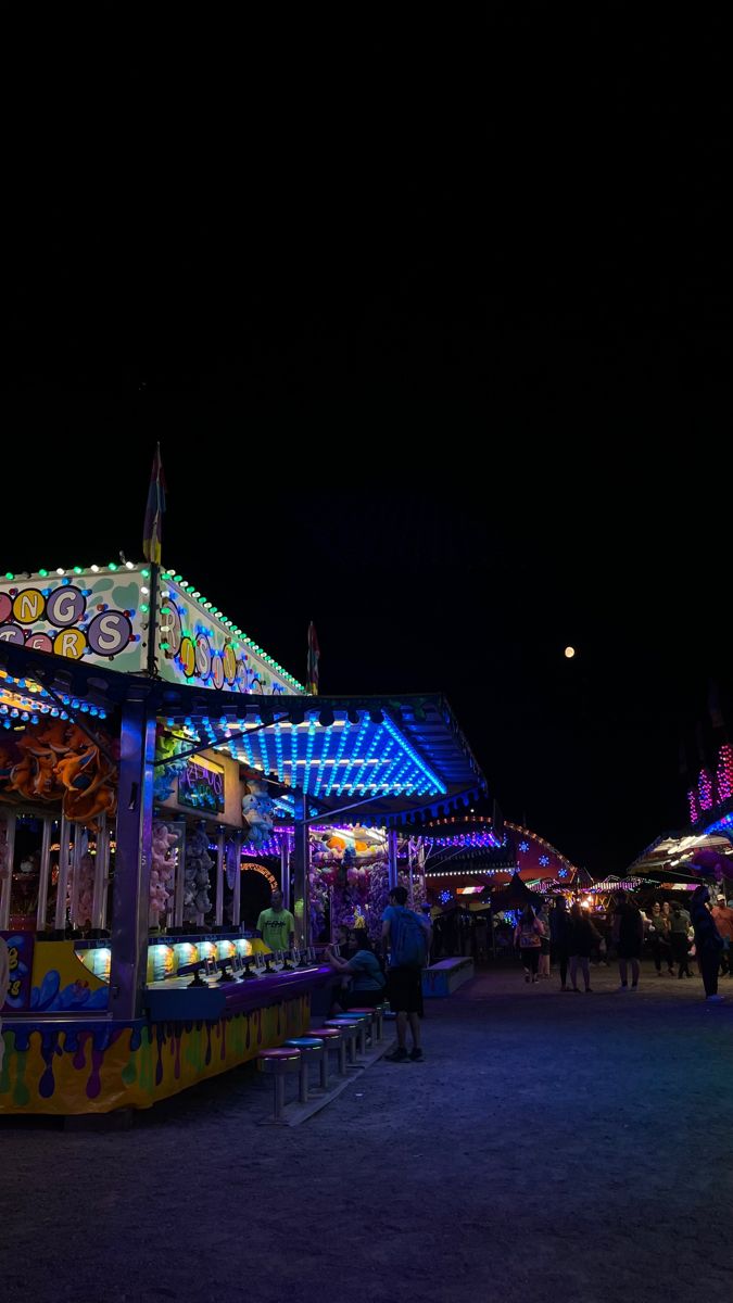 an amusement park at night with people walking around the fairground and carousels lit up