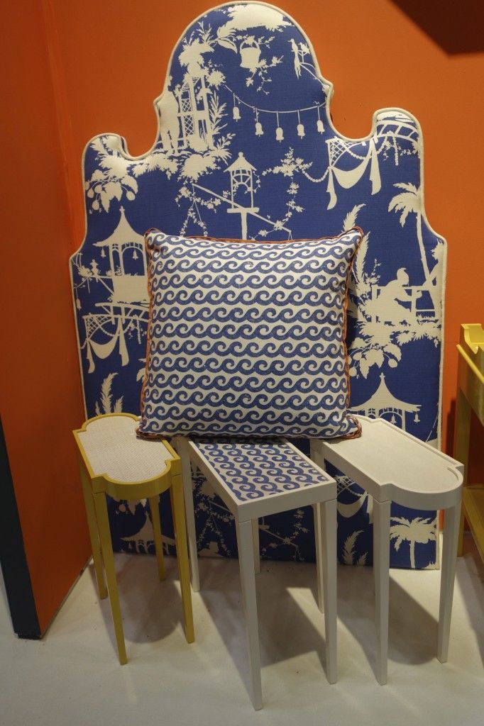 a blue and white headboard sitting next to two small tables with stools underneath it