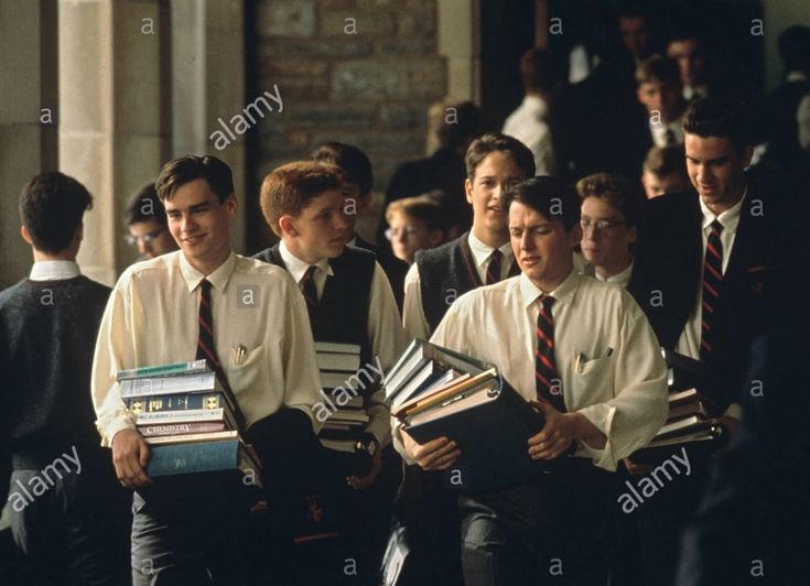 boys in school uniforms are sitting down and holding books - stock image