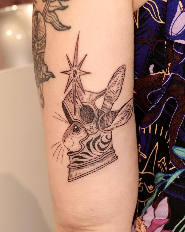 a woman with a tattoo on her arm has a crown and a rabbit in it