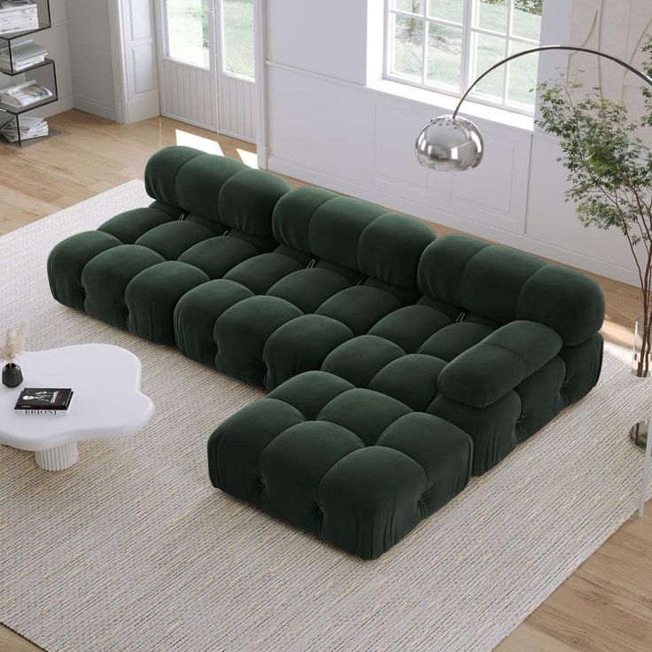 a large green couch sitting on top of a white rug