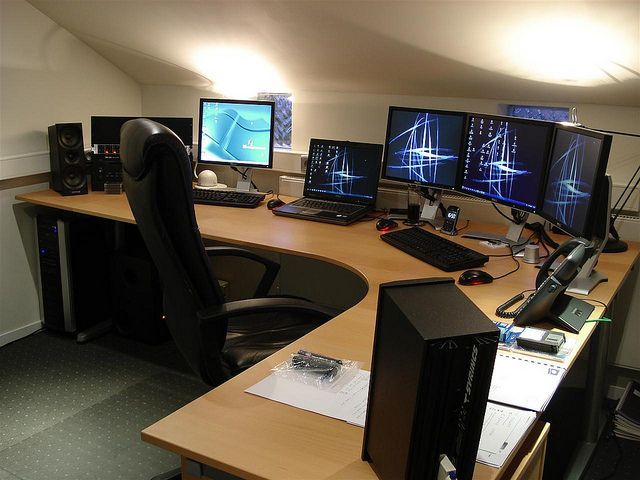 an office desk with multiple computer monitors and keyboards