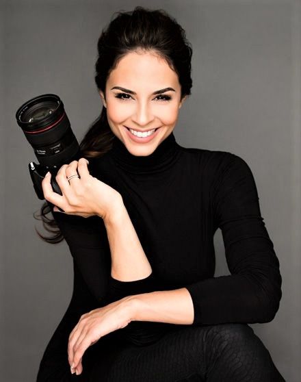 a woman is holding a camera and smiling