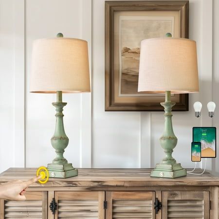 a person pointing at two lamps on top of a dresser