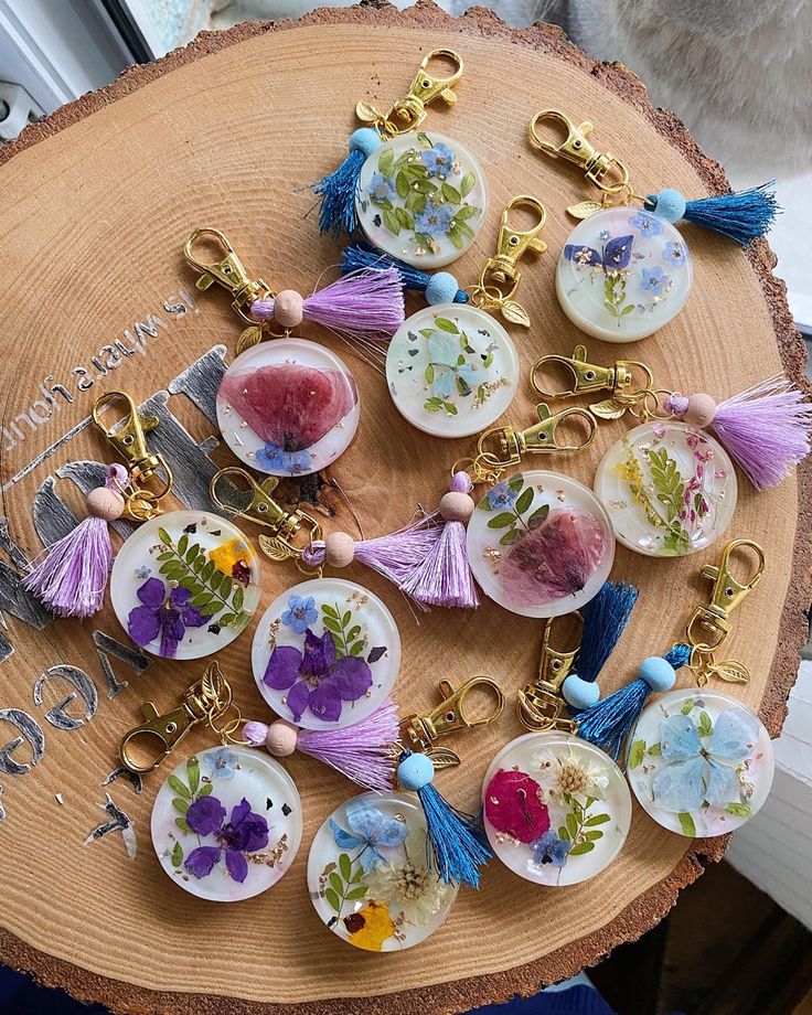 a wooden table topped with lots of different types of key chains and flowers on them