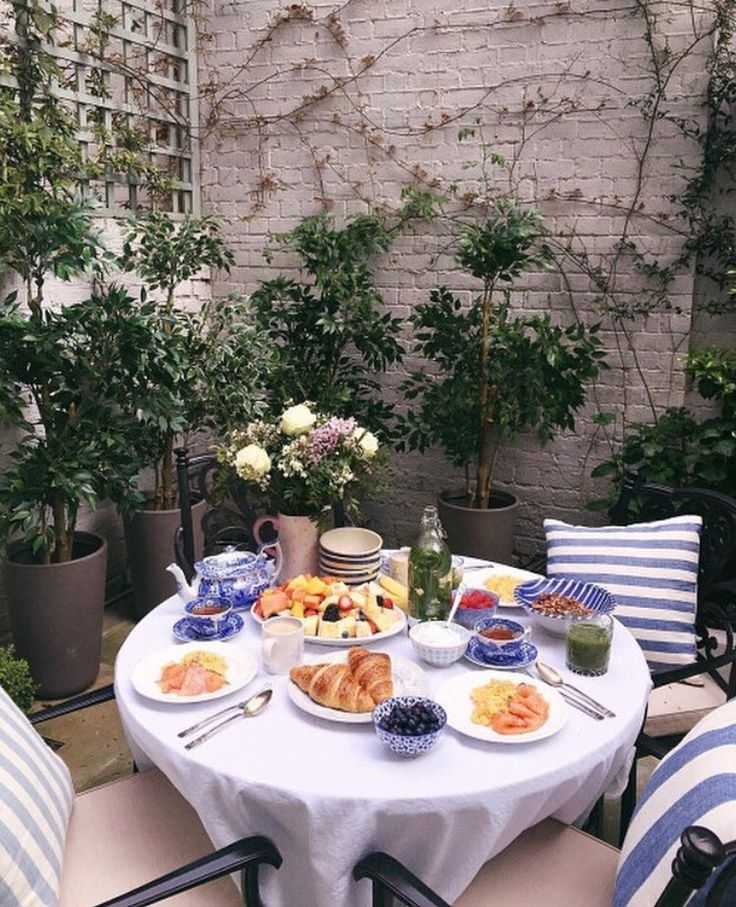 a table with food on it in front of a brick wall and potted plants