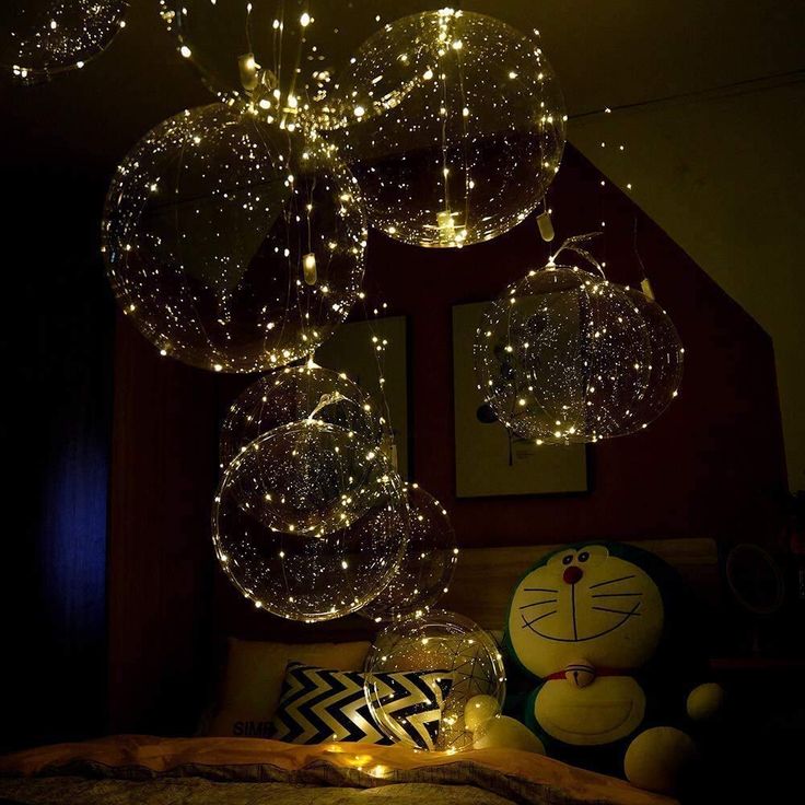 some lights that are hanging from the ceiling above a bed with pillows and pillows on it