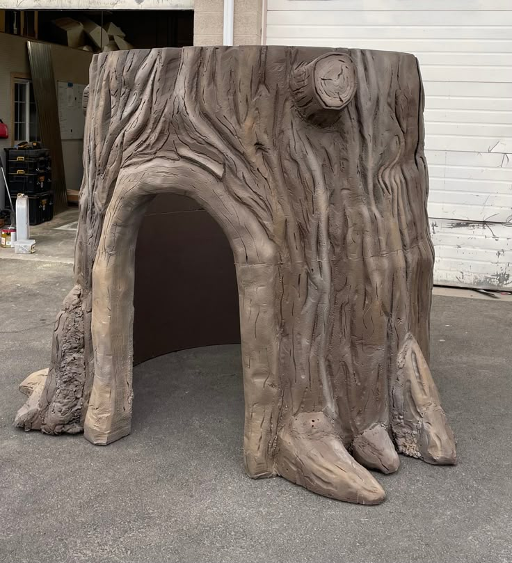 a large tree trunk with a clock on it's face in front of a garage