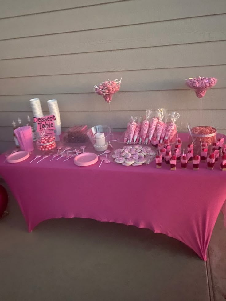 a pink table topped with lots of desserts and candy bar wrappers on top of it