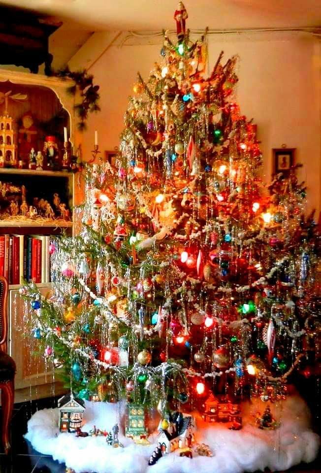 a decorated christmas tree in a living room next to a book shelf with books on it