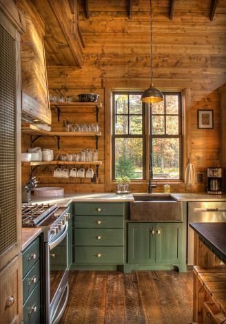 a kitchen with green cabinets and wooden walls