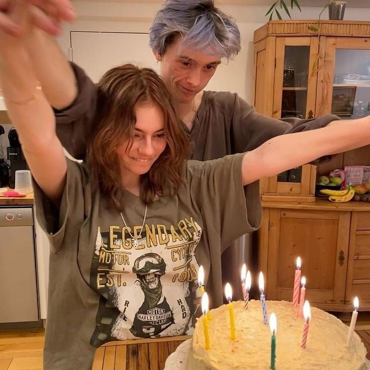 a man and woman standing in front of a cake with lit candles