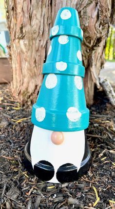 a blue and white plastic cone with polka dots on it sitting next to a tree