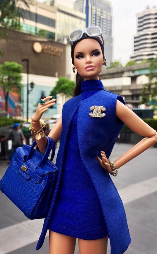 a barbie doll dressed in blue holding a purse