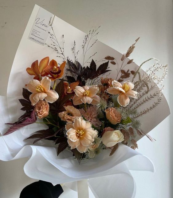 a bouquet of flowers sitting on top of a table next to a piece of paper