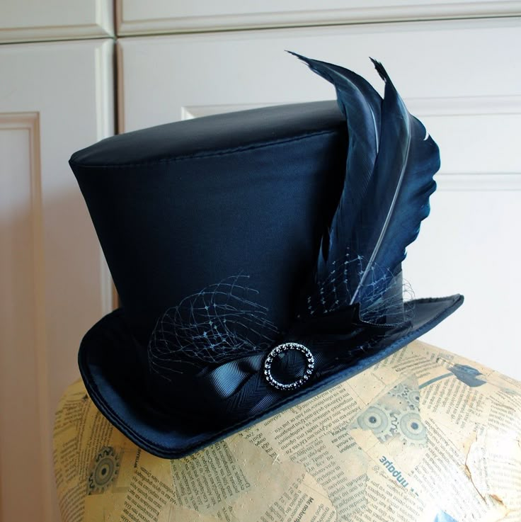 The Liza is a striking cabaret inspired full size top hat. It is covered with beautiful shiny black satin. It is decorated with black ribbon around the crown, black veil, half bow with black crystal buckle and two elegant black goose feathers. Also available as a medium size mini top hat: https://www.etsy.com/listing/256101614/victorian-witch-hatblack-mini-top?ref=shop_home_active_14 Need this TOP HAT in another color?Just send me a message to talk about a custom hat made just for you! This hat Vintage Top Hat With Curved Brim For Costume Party, Vintage Curved Brim Top Hat For Costume Party, Adjustable High Crown Top Hat For Carnival, Carnival Adjustable Top Hat With High Crown, Black Gothic Hat For Costume, Adjustable Short Brim Top Hat For Carnival, Gothic Black Top Hat For Costume Party, Black Gothic Top Hat For Costume Party, Gothic Mini Hats For Carnival Costume