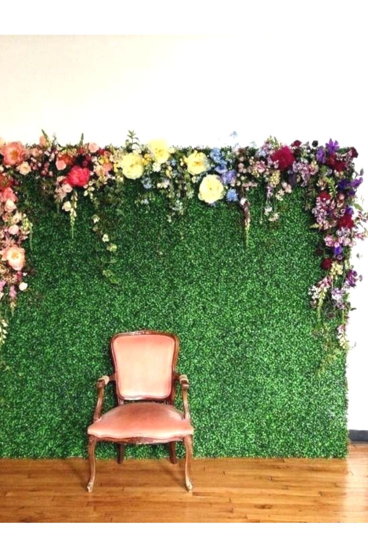 a chair sitting in front of a green wall with flowers on it and a wooden floor